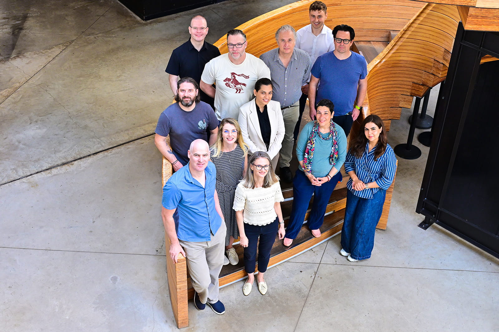 Members of the Gamification and Systems Thinking Lab gather for a photo on a curved wooden staircase during an away day at the Royal Botanic Garden Edinburgh.