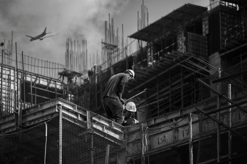 Two construction workers busy themselves installing steel reinforcement on an active building site