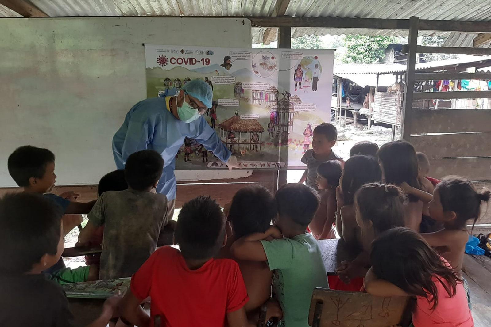 A group of school children gather around an information board during a lesson about Covid-19